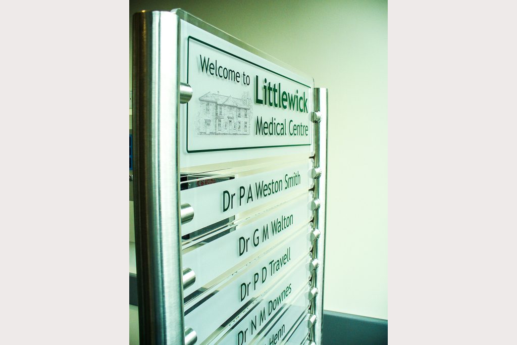 Post mounted doctors names sign in corridor of surgery,