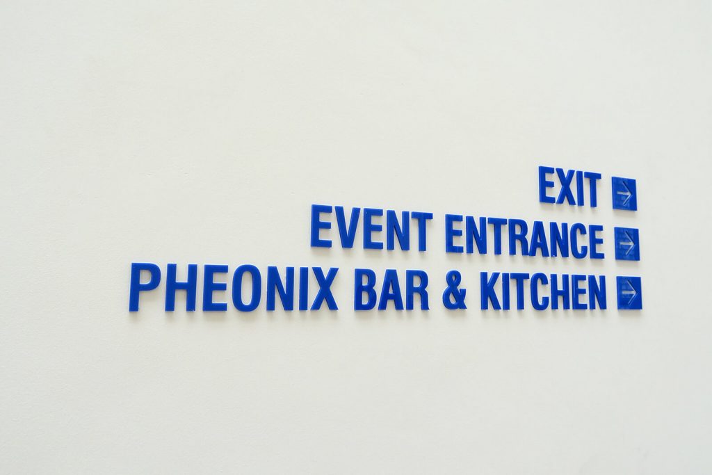 CNC coloured acrylic lettering installed to white wall to display directions to exit. entrance and kitchen.